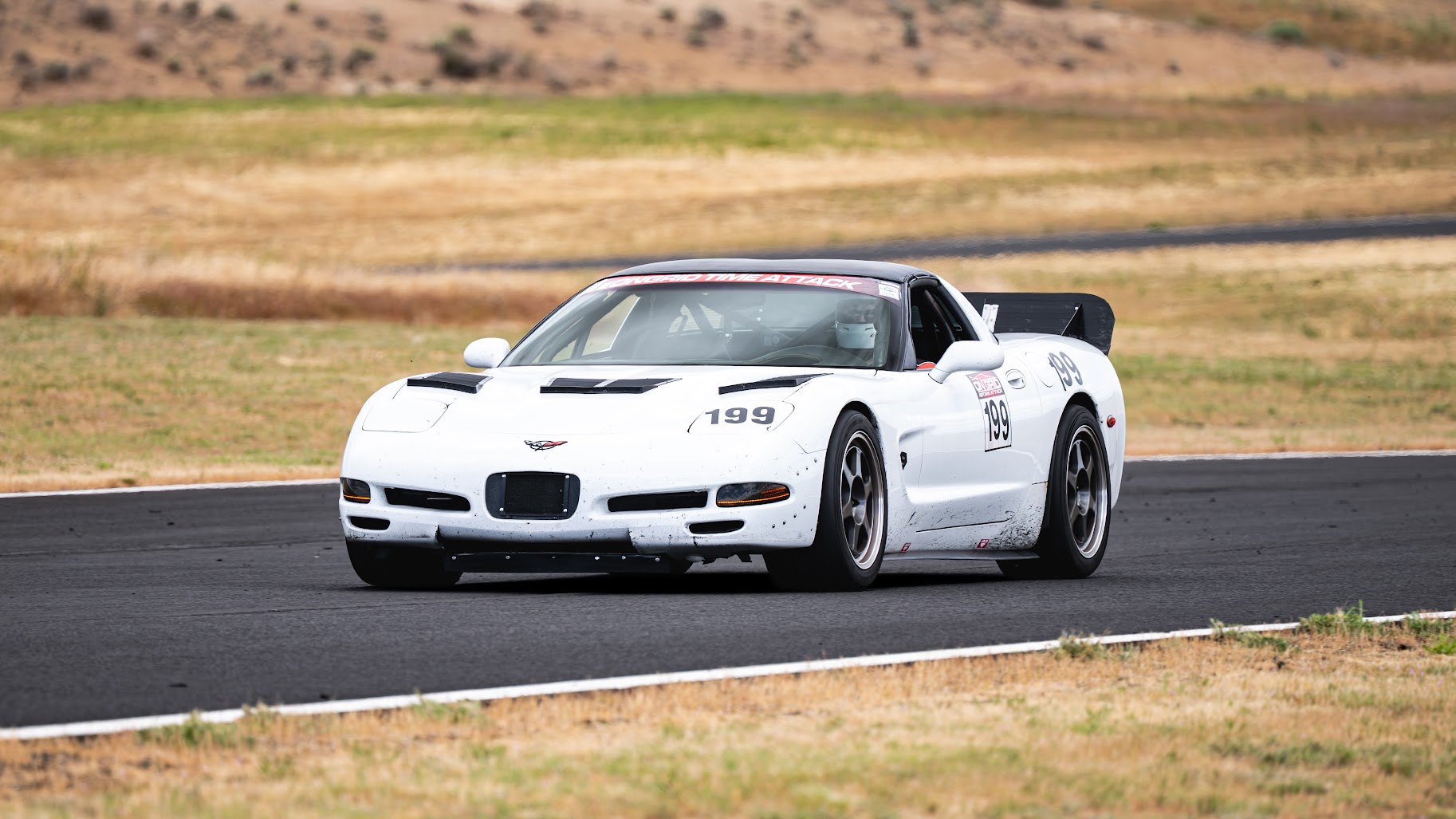 White C5 Corvette driving on a race track.
