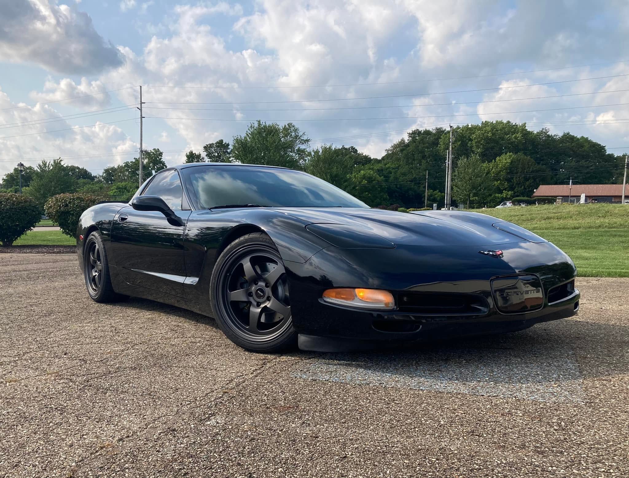An all black stock C5 Corvette, pictured from the front passenger side