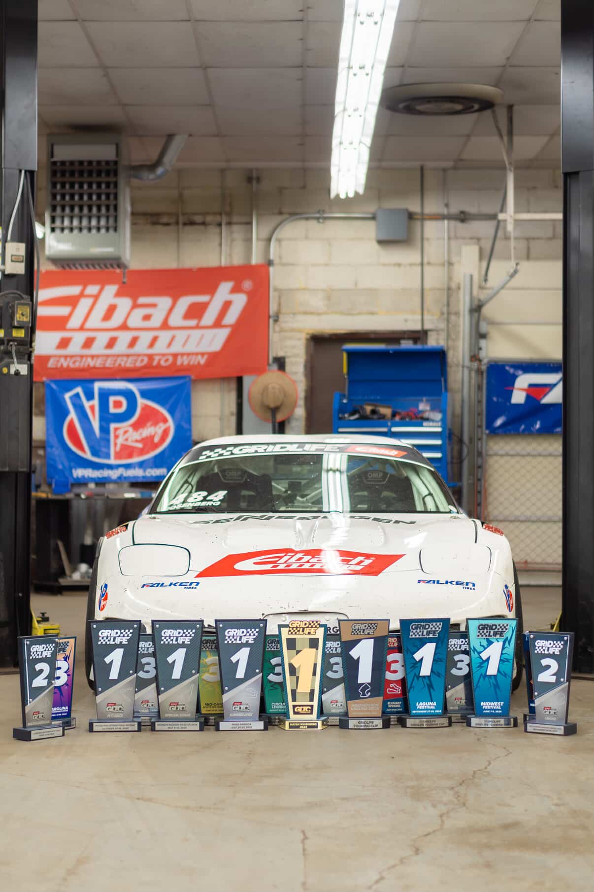 Matan Rosenberg's C5 Corvette in front of a very large amount of OnGrid trophies.