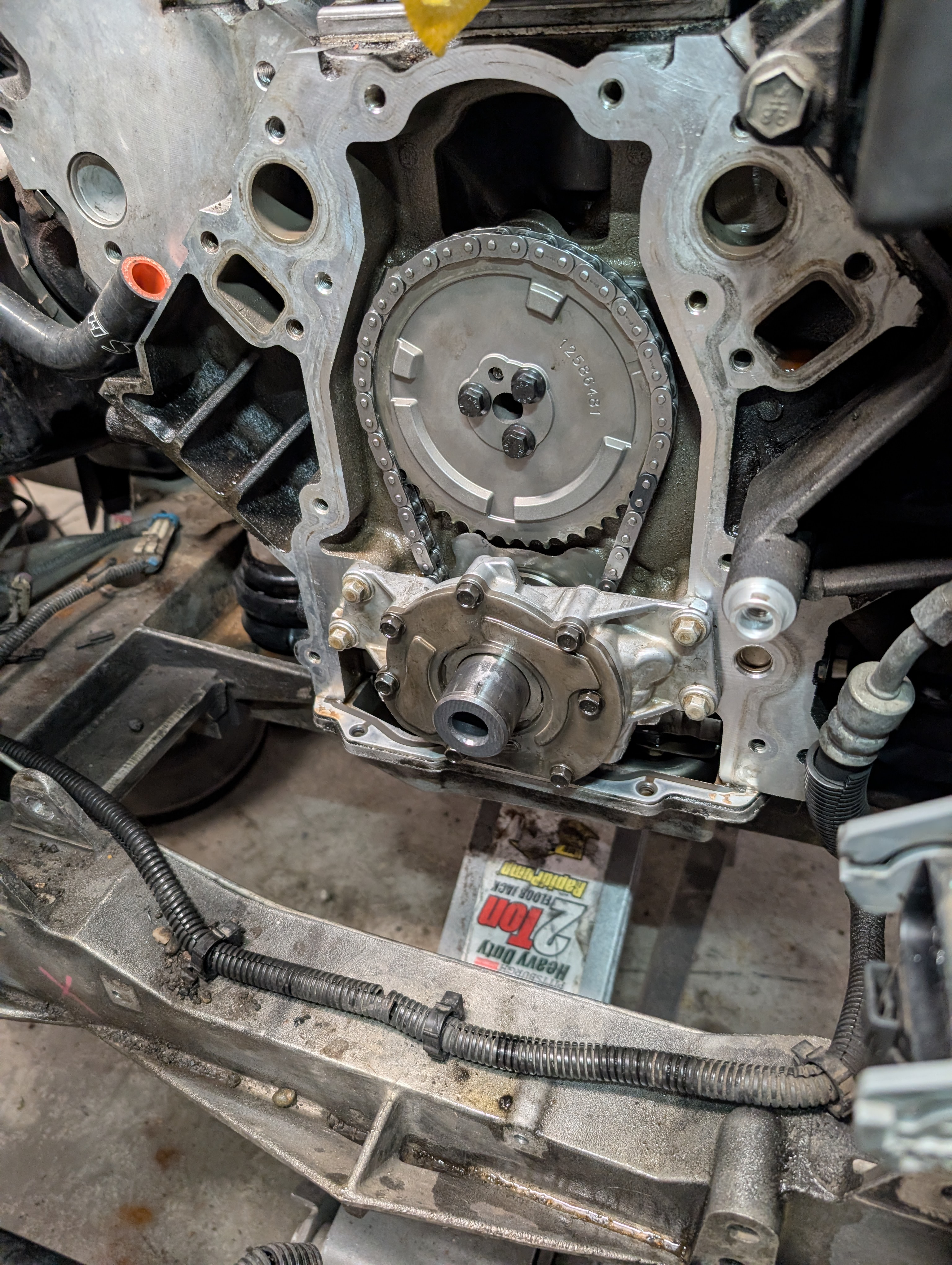 The front of a C5 Corvette engine with the harmonic balancer and timing cover plate removed to show the oil pump and the cam chain.