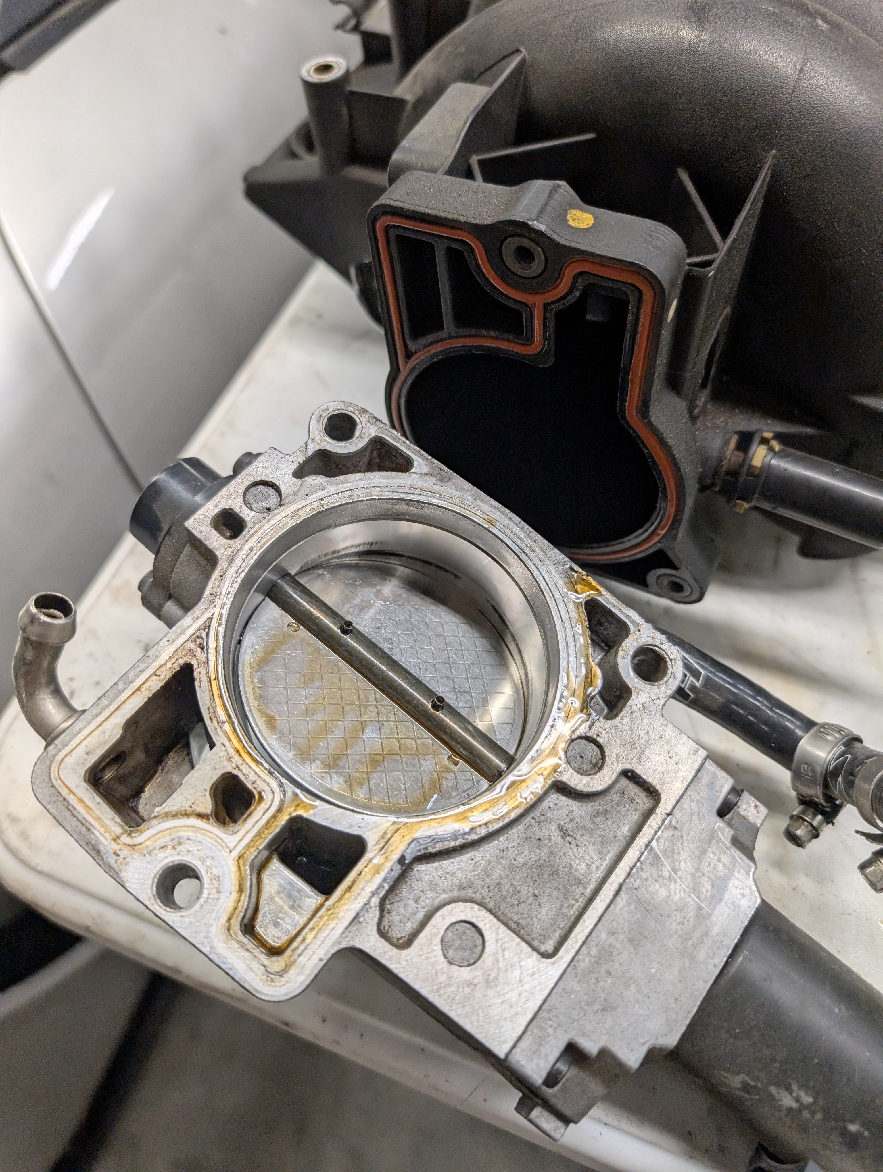 The throttle body and throttle body "snout" on a C5 Corvette LS1, demonstrating the need for a new gasket.