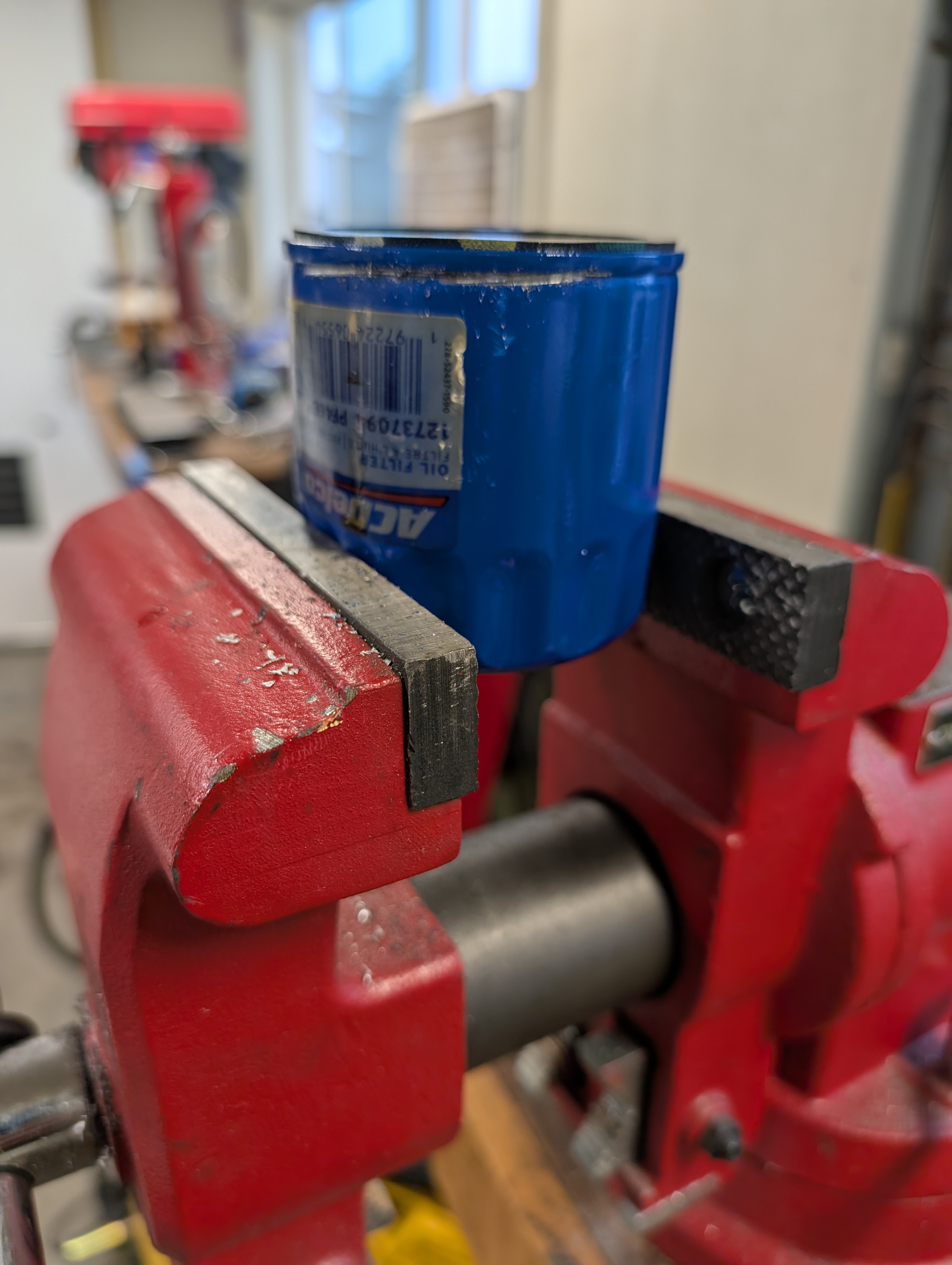 An oil filter in a vice, about to be cut to expose the internal material for checking for metal.