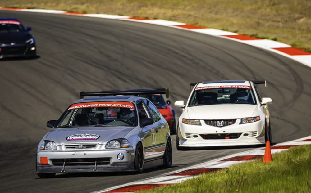 Cars driving around at a Time Attack Event with the OnGrid time attack banner on their cars