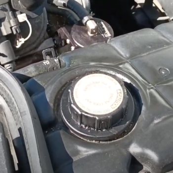 An example of a C5 Corvette expansion tank with a failed radiator hose connection that is ever so slightly spurting out coolant.