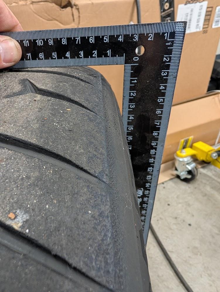 A measuring square pressed up against the outside of a Continental Extreme Contact Force tire to demonstrate side profile.