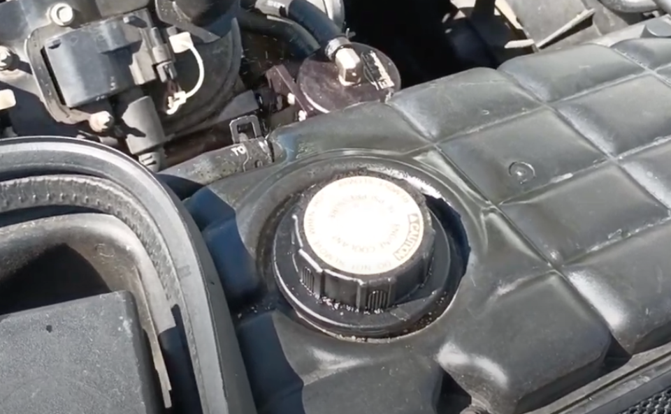 An example of a C5 Corvette expansion tank with a failed radiator hose connection that is ever so slightly spurting out coolant.