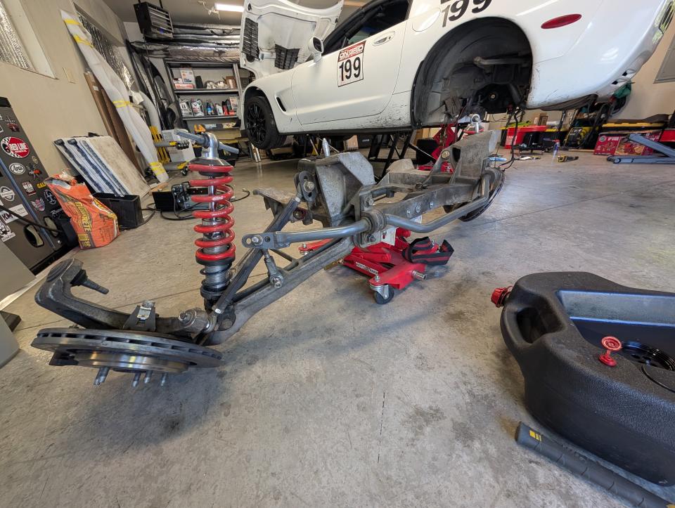 The rear subframe of a C5 Corvette removed from the car and sitting on a transmission dolly